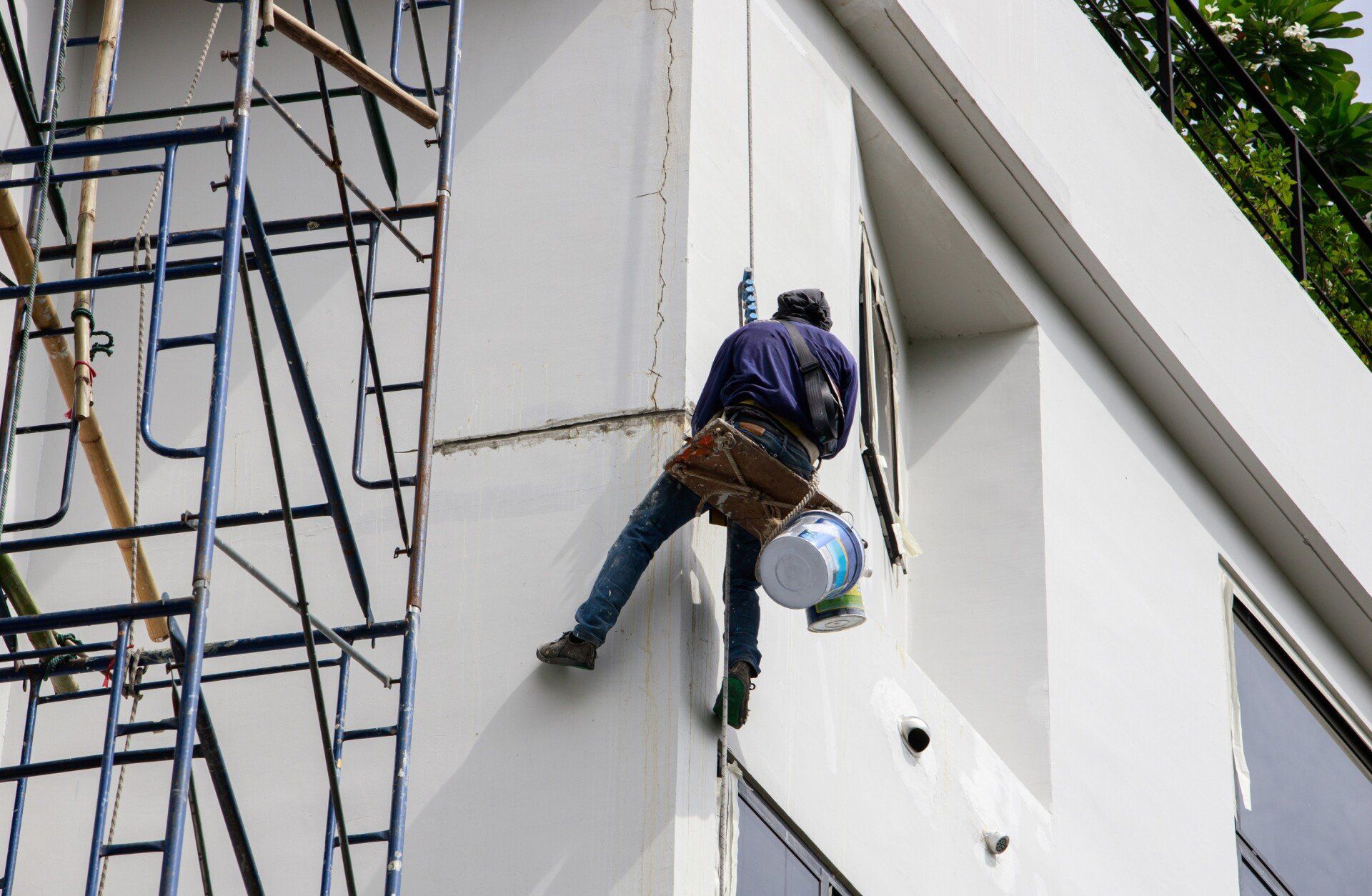a local painter hanging by rope, painting the exterior of this building in Coral Springs FL
